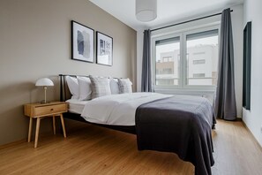 Une chambre à coucher moderne avec un lit, une table de chevet, une lampe et une œuvre d’art accrochée au mur.