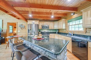 A spacious kitchen with granite countertops, wooden cabinets, and a large island with bar stools.