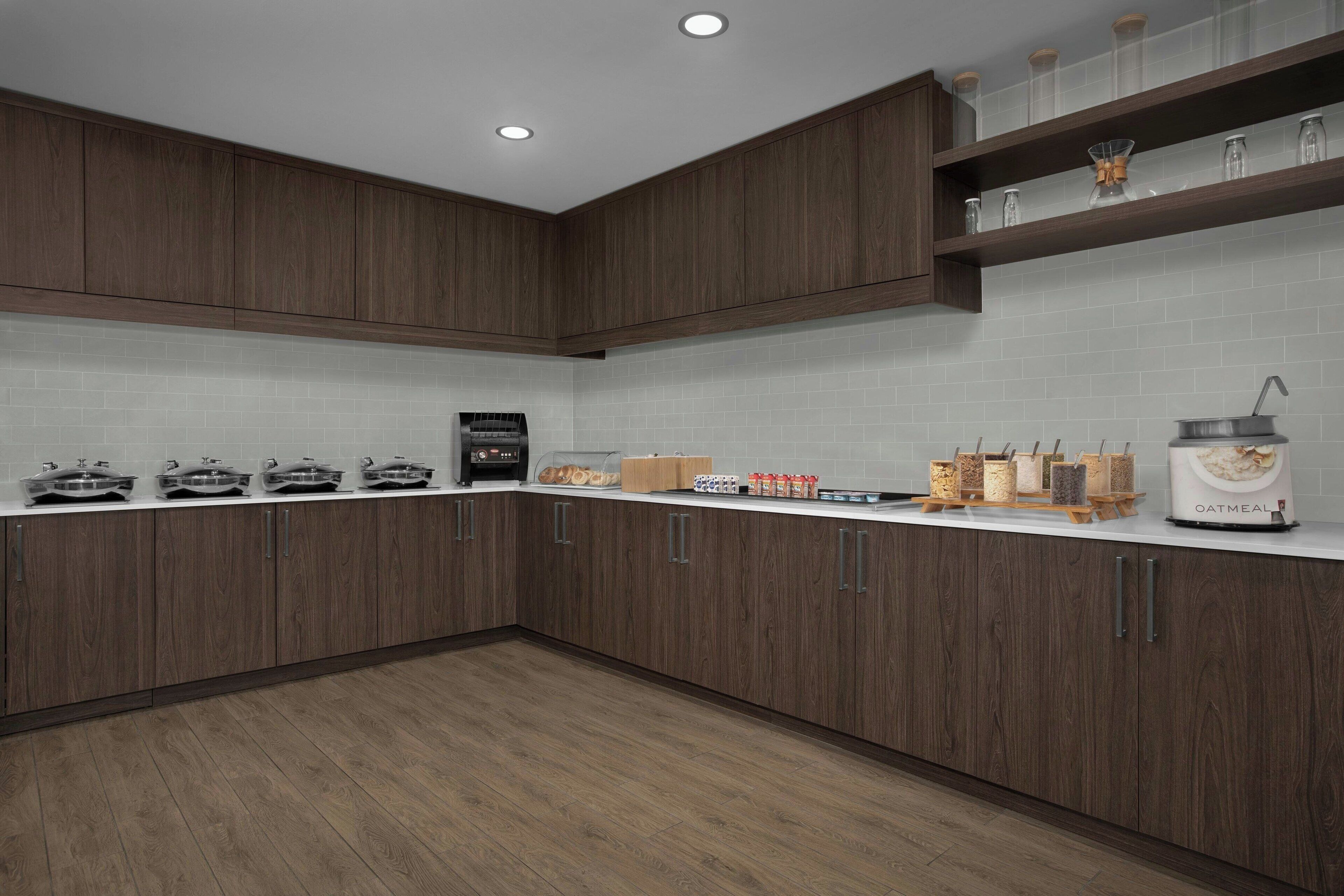 A modern kitchen with wooden cabinets, a white countertop, and various kitchen appliances.