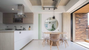 A modern kitchen with a dining area, featuring a central island, wooden cabinets, and a large mirror above the table. - Cool 3 BR W/ Balcony in Laureles Medellín (Medellín)