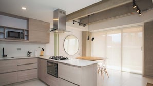 A modern kitchen with a central island, built-in microwave, and stainless steel range hood. - Cool 3 BR W/ Balcony in Laureles Medellín (Medellín)