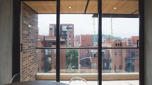 A room with a large window offering a view of surrounding buildings and a clear sky. - Cool 3 BR W/ Balcony in Laureles Medellín (Medellín)