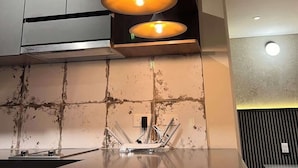 A modern kitchen with three pendant lights, a stainless steel range hood, and a marble countertop. - Stunning Studio in Candelaria (Bogotá)