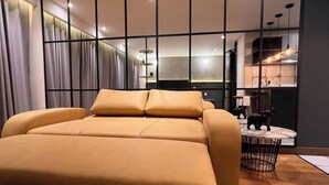 A modern bedroom with a large bed, a dining area, and a kitchen visible through a glass partition. - Stunning Studio in Candelaria (Bogotá)
