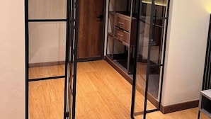 A room with a wooden floor, a sliding glass door closet, and a built-in shelving unit. - Stunning Studio in Candelaria (Bogotá)