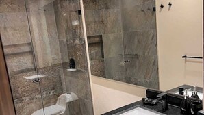 A modern bathroom with a glass-enclosed shower, a toilet, and a vanity with a sink. - Stunning Studio in Candelaria (Bogotá)