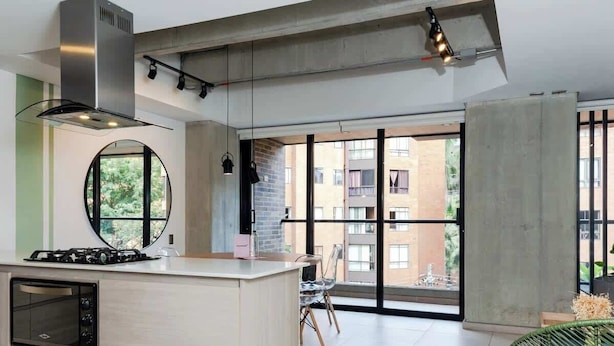 Eine moderne Küche mit Kochinsel, Einbauofen und großem Fenster mit Blick auf die Stadt.