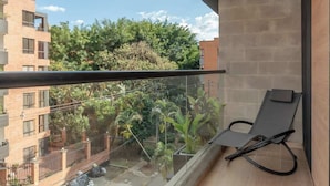 Ein Balkon mit Blick auf eine Wohngegend, ein Stuhl und eine Holzbalkendecke.