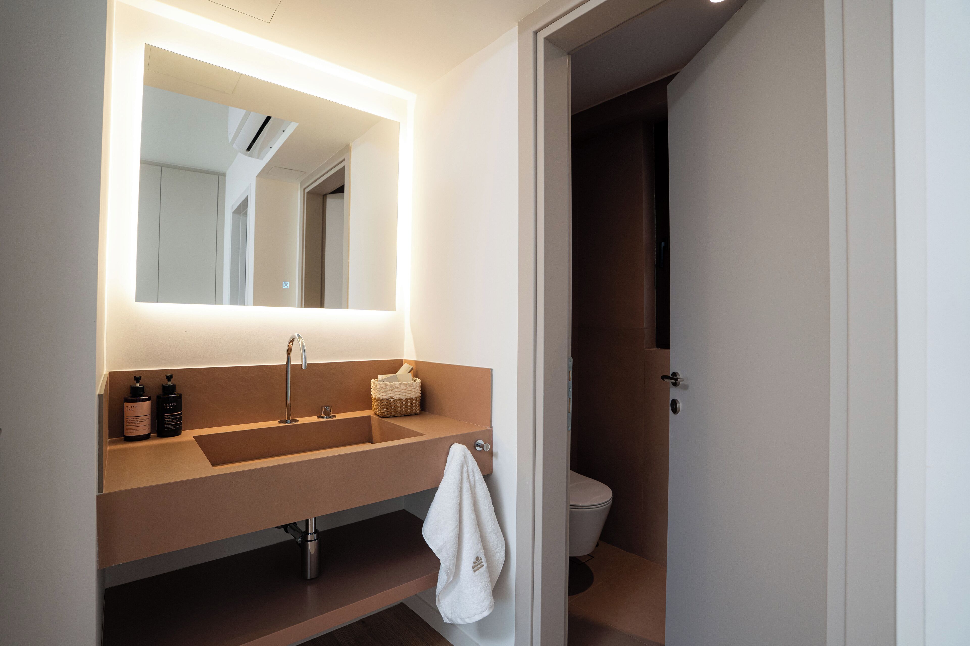A modern bathroom with a large mirror, a sink, and a toilet.