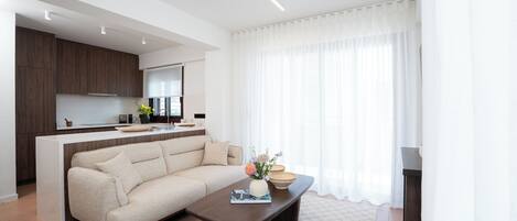A modern living room with a sofa, coffee table, and a kitchen area in the background.