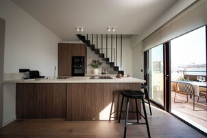 Una cocina moderna con una isla central, una escalera y vistas al exterior.