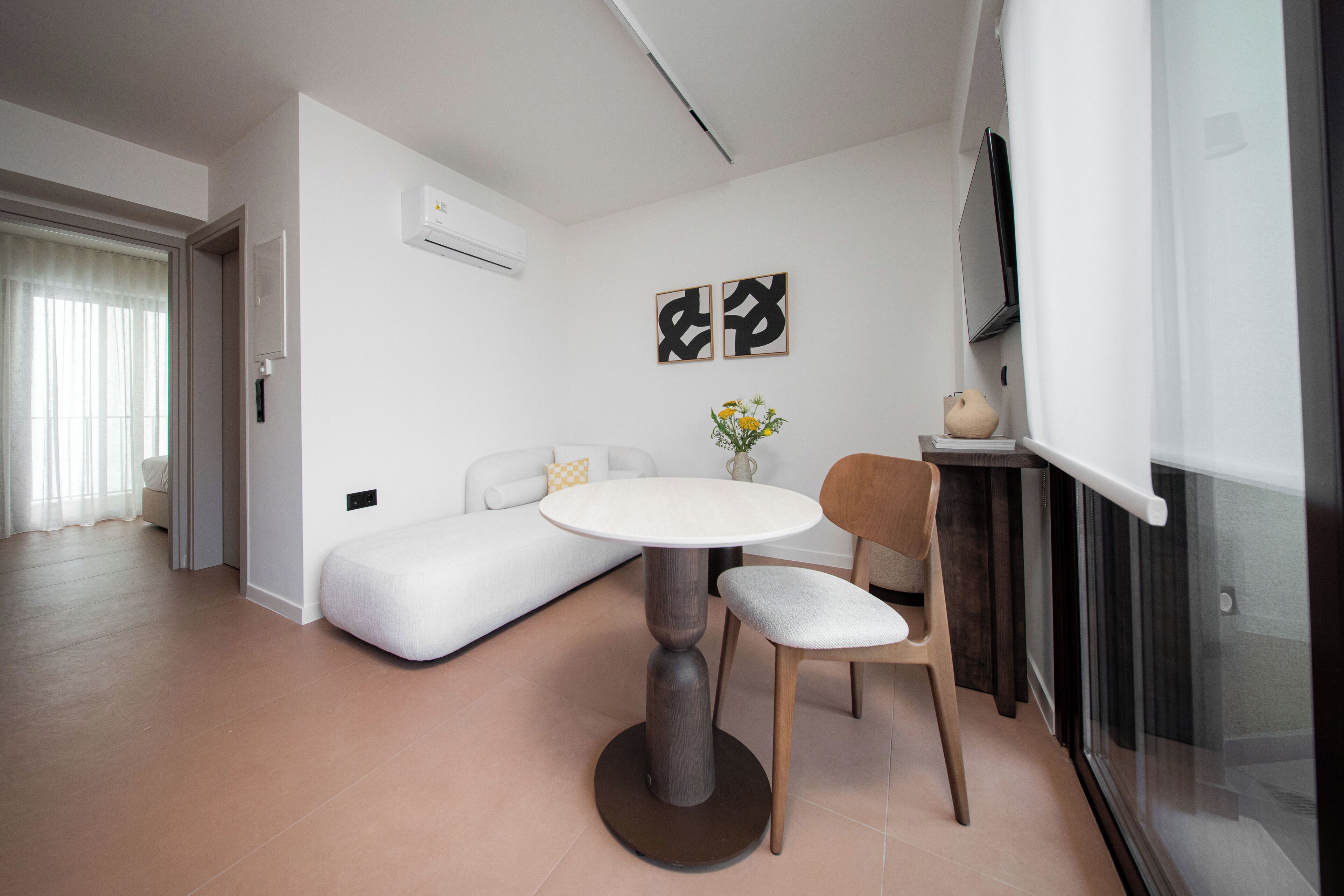 Un salon moderne avec une table ronde, un canapé et un téléviseur fixé au mur.