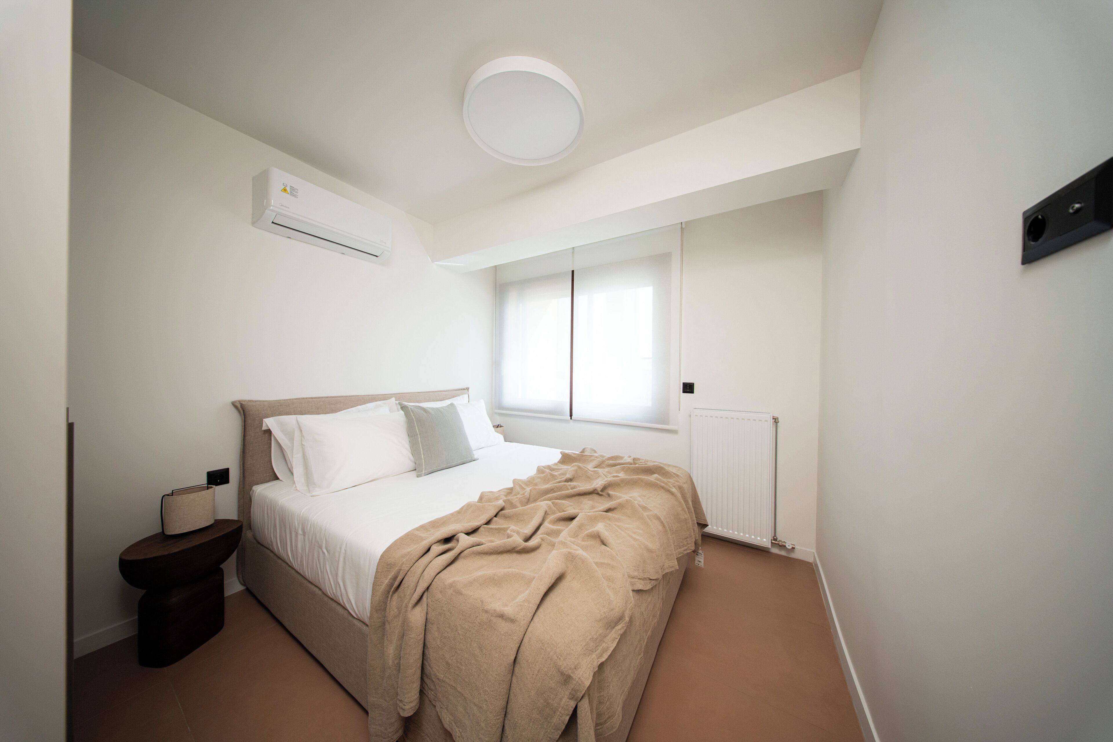 Een slaapkamer met een bed, nachtkastje en een raam.