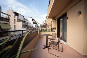 Un balcón con una mesa y sillas, con vistas a un área residencial con varios edificios.