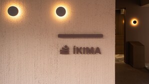 Eine Wand mit zwei runden Leuchten und einem Schild mit der Aufschrift 'IKIMA'.
