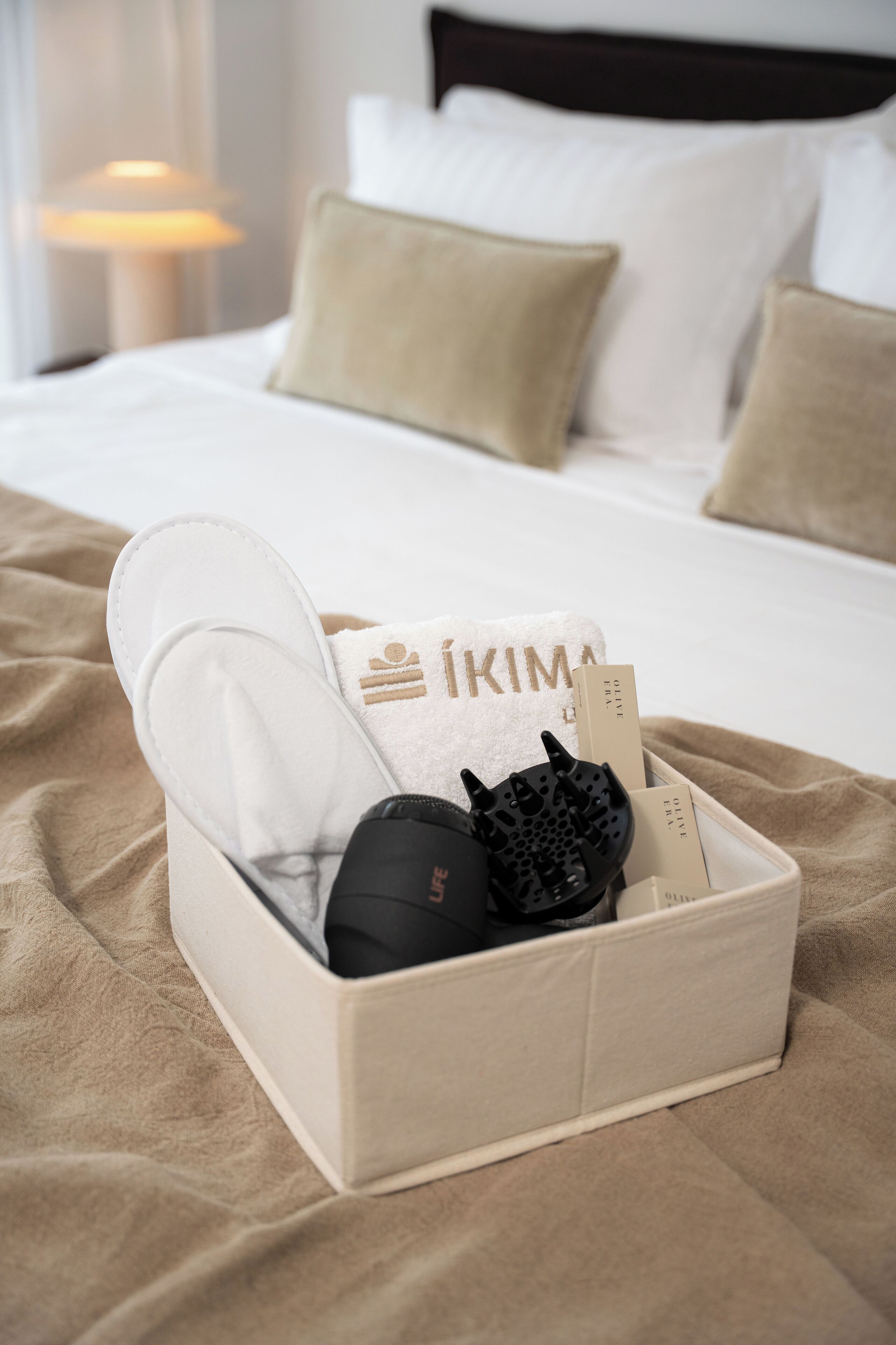 A neatly made bed with a beige blanket, a white pillow, and a white pillowcase.