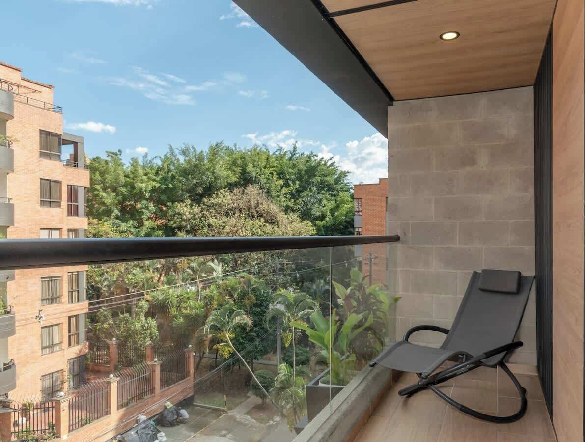 Ein Balkon mit Blick auf eine Wohngegend, ein Stuhl und eine Holzbalkendecke.