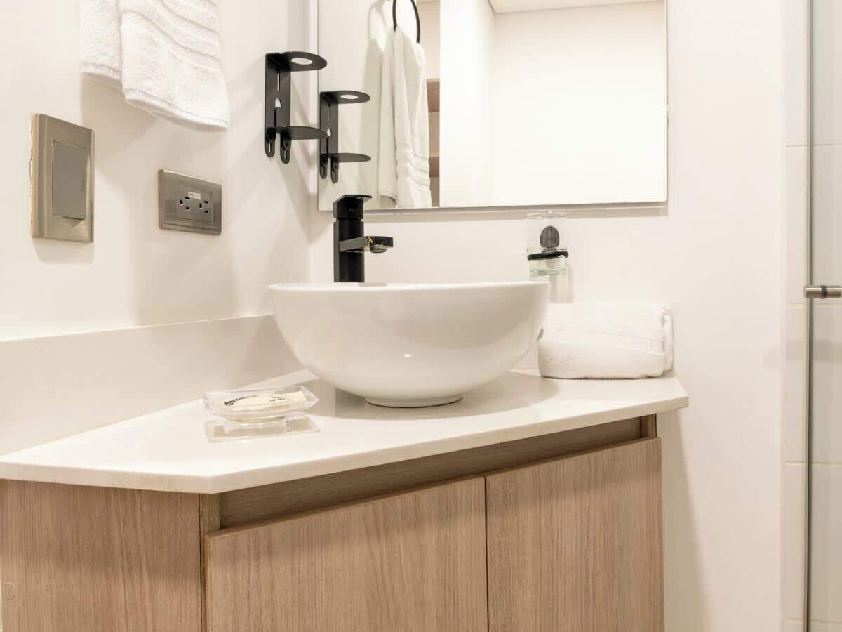 Un bagno moderno con un lavandino bianco, uno specchio e un porta asciugamani.