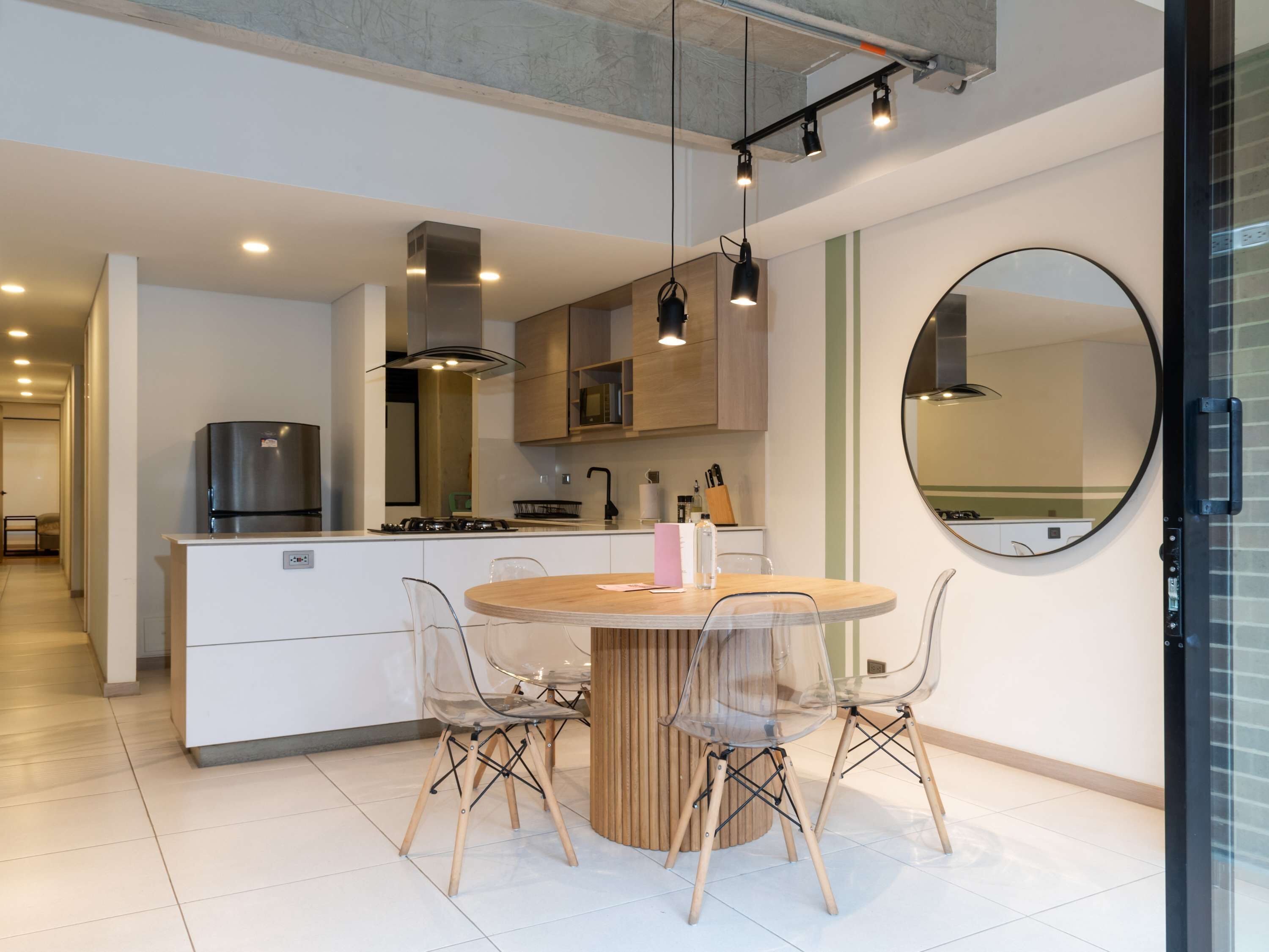 Une cuisine moderne avec un îlot central, des chaises transparentes et une table à manger ronde.