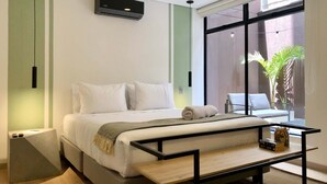 Ein modernes Hotelzimmer mit Bett, Nachttisch und Blick ins Freie.