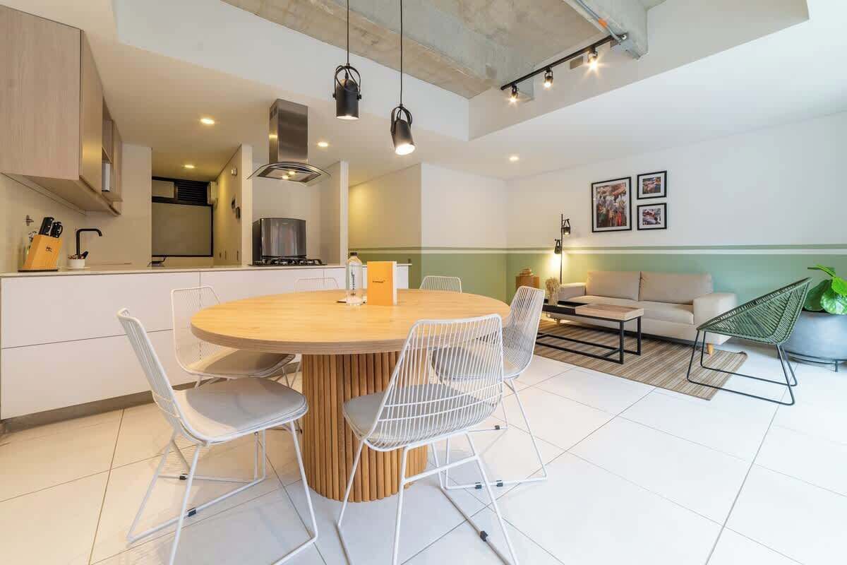 A modern kitchen with a central island, white chairs, and pendant lighting.