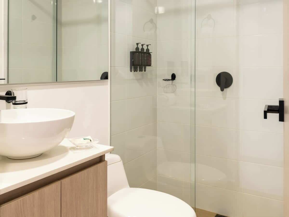 A modern bathroom with a white sink, mirror, and glass shower enclosure.