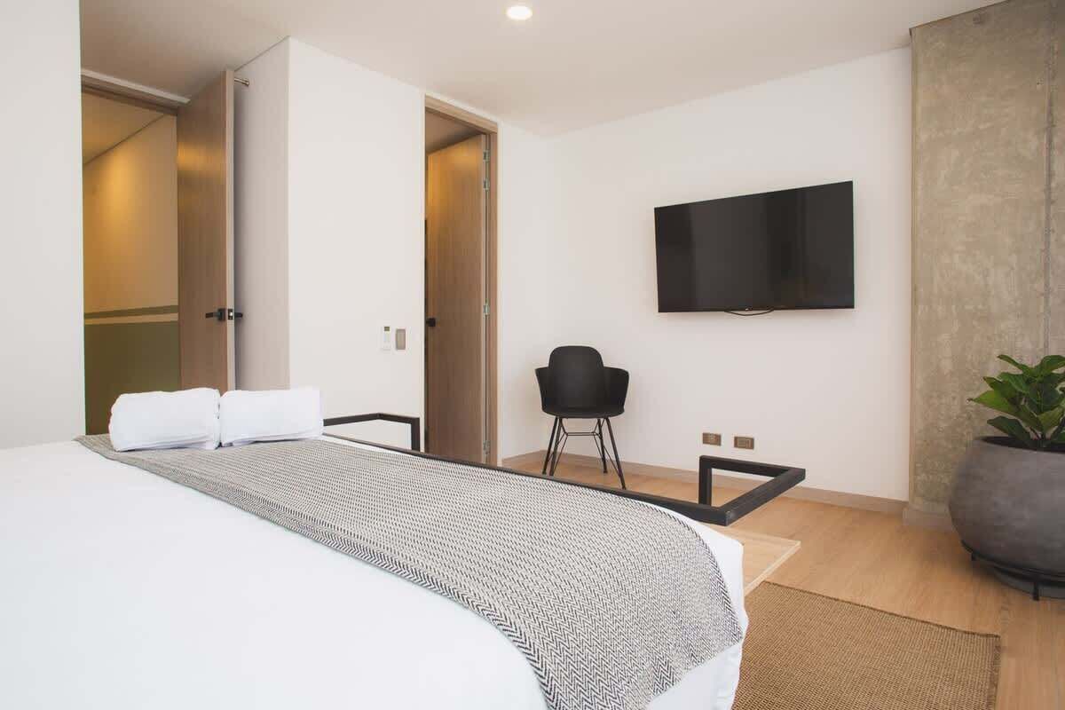 Ett modernt hotellrum med en stor säng, en platt-TV som är monterad på väggen och en krukväxt.