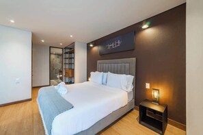 Une chambre d’hôtel moderne avec un grand lit, une table de chevet avec une lampe et une œuvre d’art accrochée au mur.