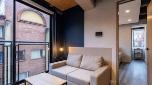 A modern living room with a sofa, a coffee table, and a view of a brick building through large windows. - Amazing Loft in Chapinero (Bogotá)