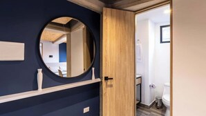 A modern bathroom with a wooden door, a round mirror, and a white toilet. - Amazing Loft in Chapinero (Bogotá)