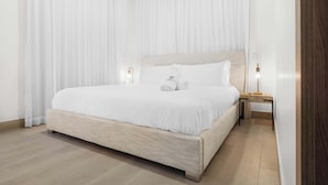 A neatly made bed with white linens, a wooden headboard, and two bedside lamps. - Stylish 3BR Villa by Vistacana Rentals (Punta Cana)