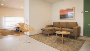 A modern living room with a sectional sofa, a wicker chair, and a small coffee table. - Splendid Studio in Laureles in Medellín (Medellín)