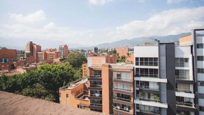 A cityscape with modern buildings, including a prominent multi-story structure with balconies and a flat roof. - Splendid Studio in Laureles in Medellín (Medellín)