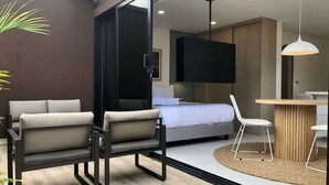A modern interior with a bed, a TV mounted on the wall, and a dining area with a table and chairs. - Cozy Studio w/ Balcony in Laureles Medellín (Medellín)