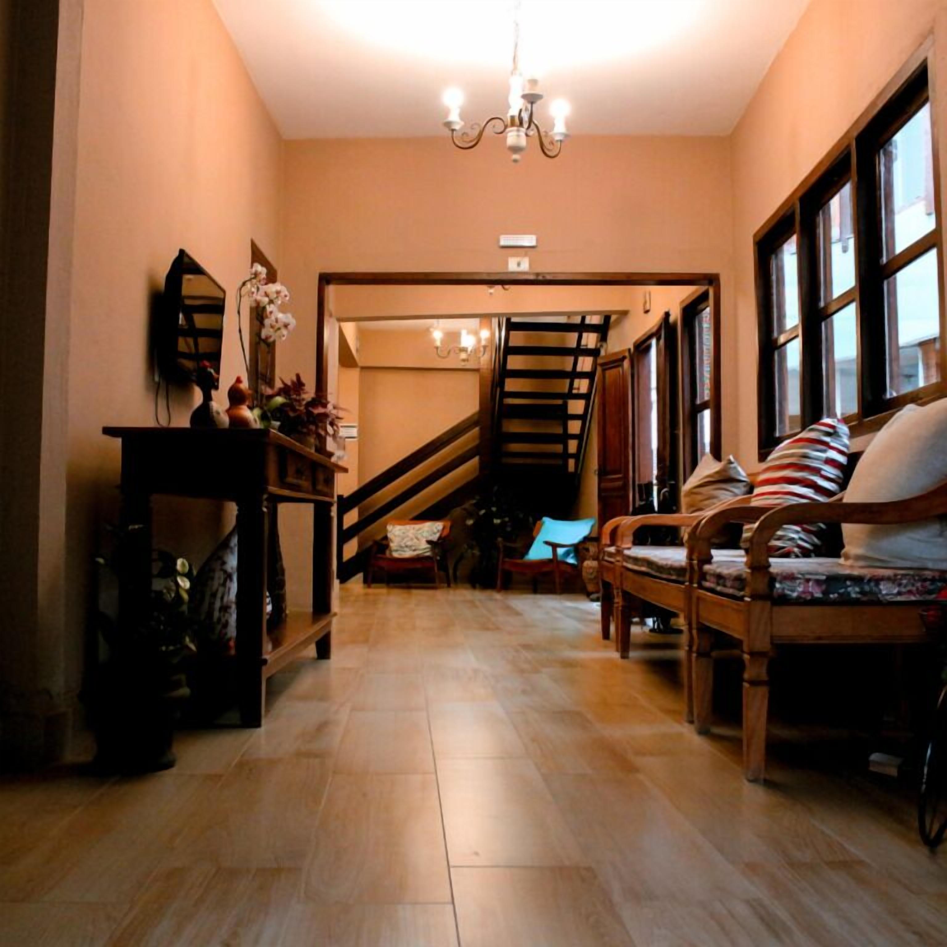 Ein Flur mit Treppe, Holzmöbeln und einem Chandelier.