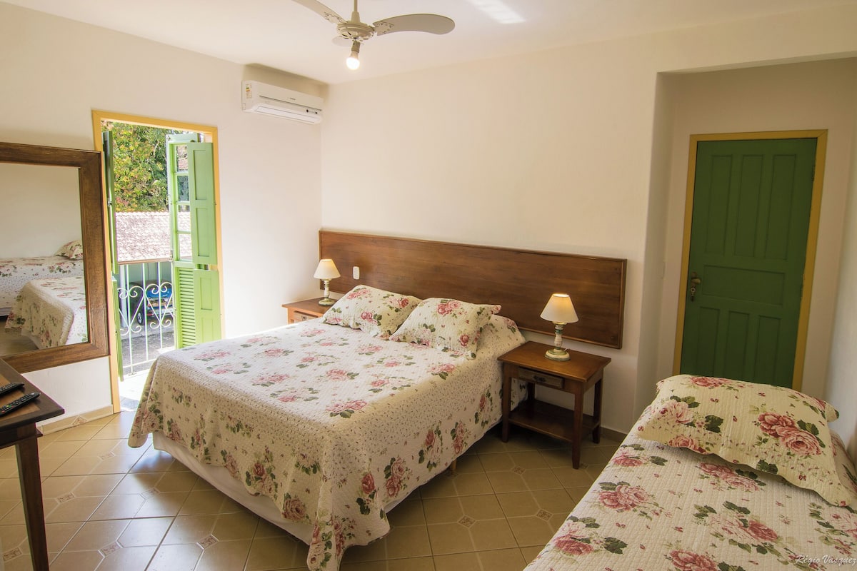 Ein Schlafzimmer mit einem großen Bett, zwei Nachttischen, einem Spiegel und einer grünen Tür.