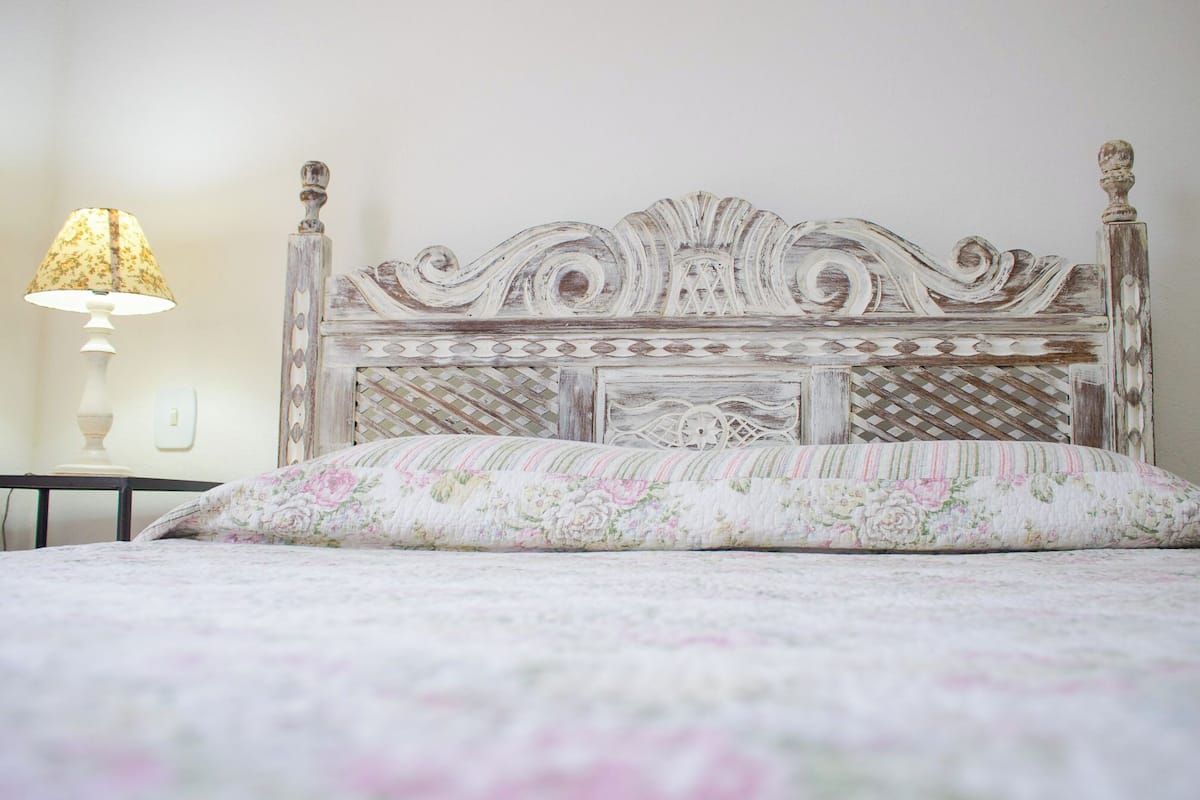 Ein Bett mit einem blumigem Bettbezug und einem dekorativen Kopfteil.