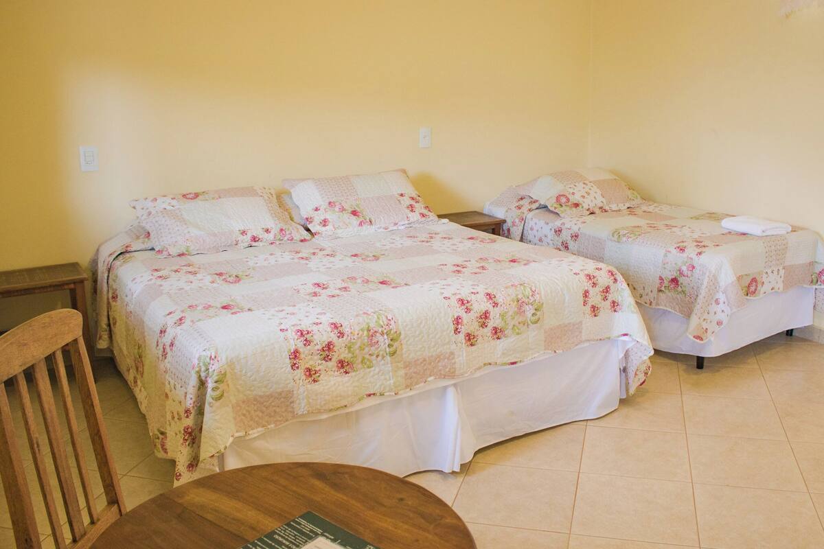 Ein Zimmer mit zwei Einzelbetten, einem Holzstuhl und einem kleinen runden Tisch.