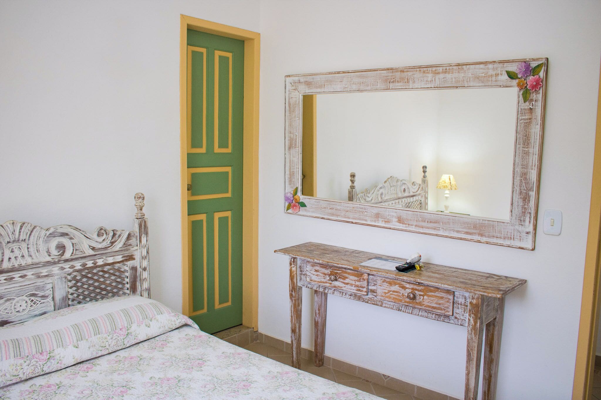 A bedroom with a bed, a dresser, a mirror, and a green door.
