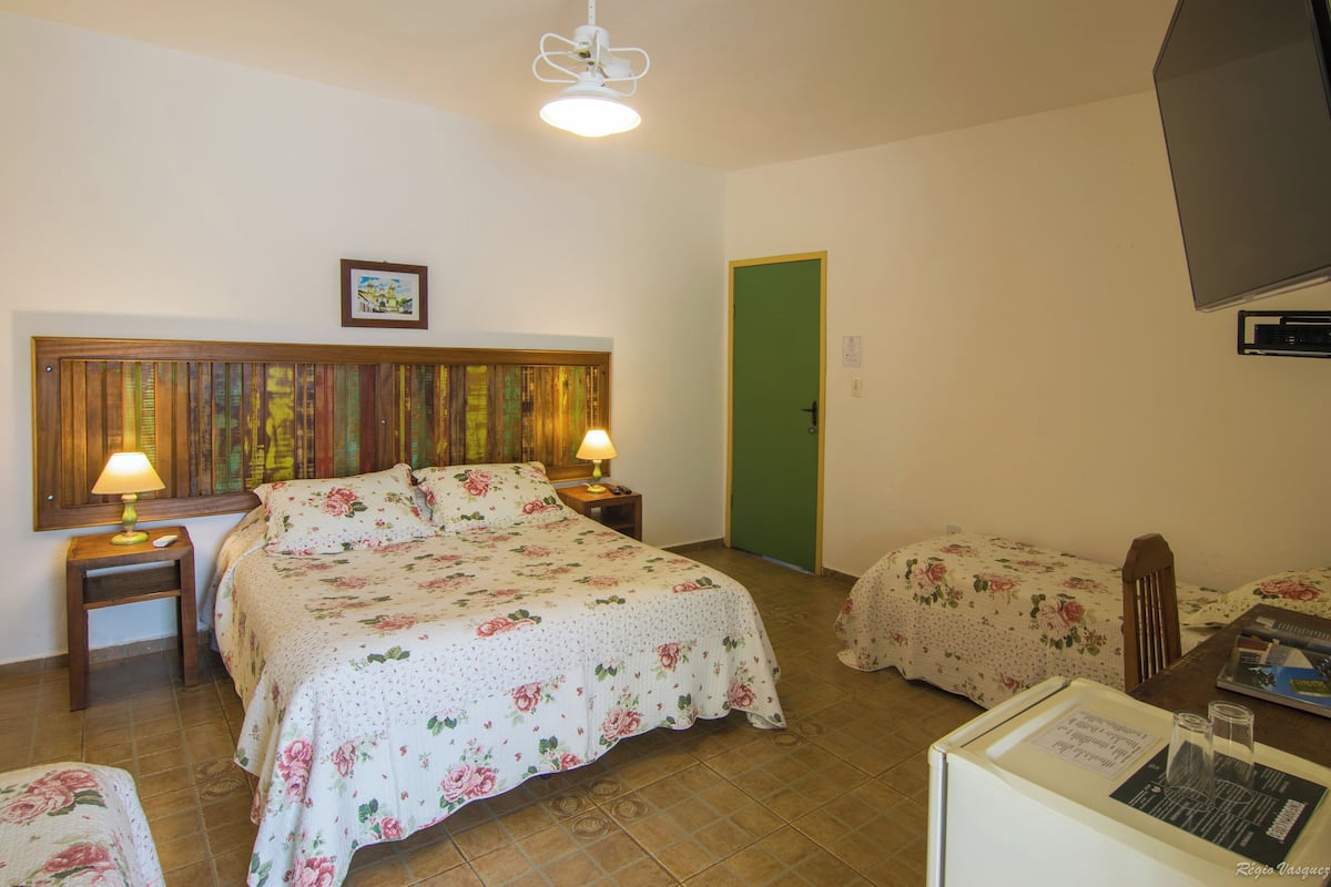 Ein Schlafzimmer mit zwei Betten, einem Holzkopfende, Nachttischlampen, einem gerahmten Bild und einer grünen Tür.