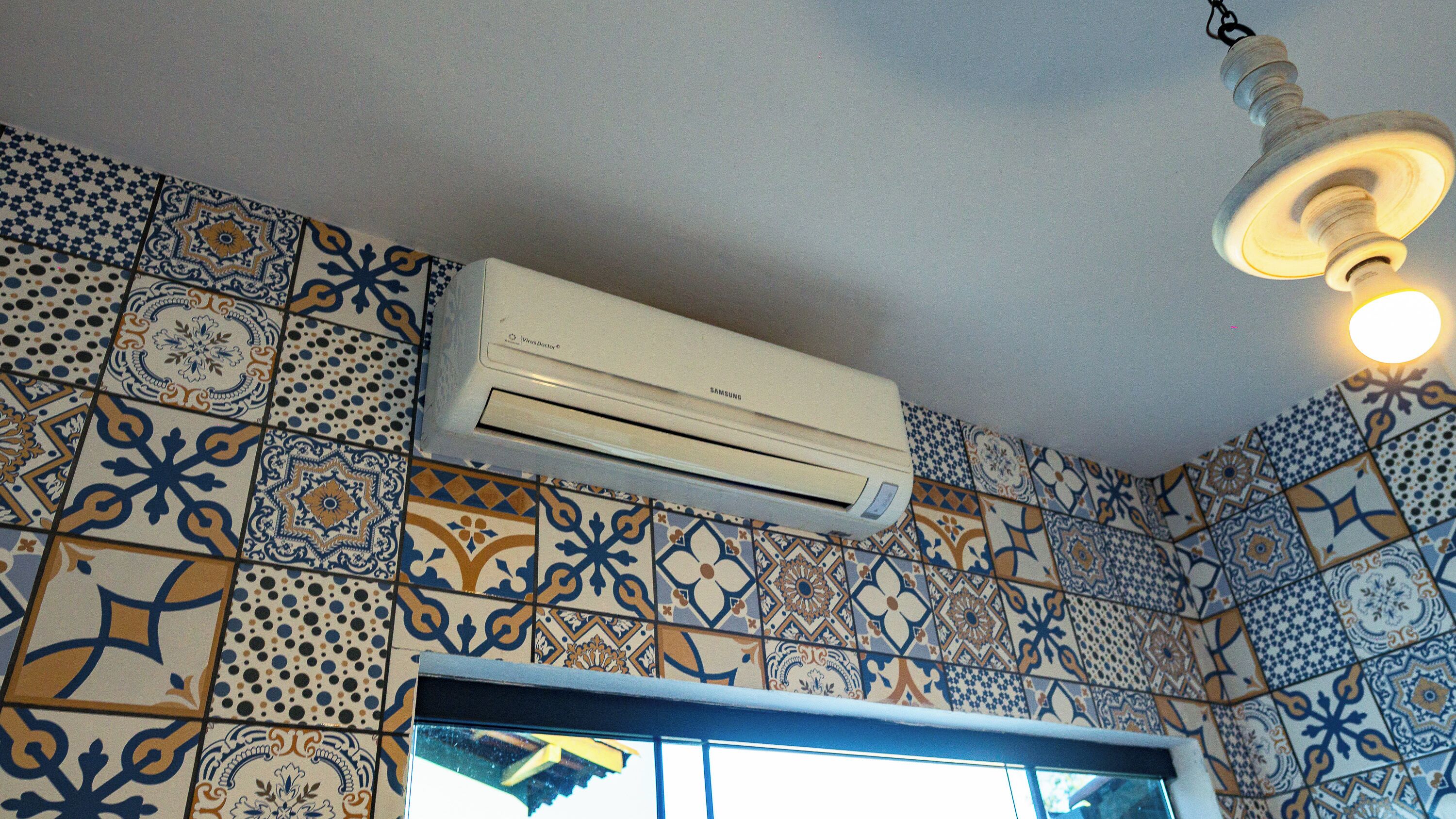 A room with patterned tiles, a Samsung air conditioner, and a ceiling light fixture.