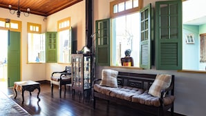 A room with a wooden bench, a small table, and a cabinet with glassware. - Pousada da Sirlei (Tiradentes)