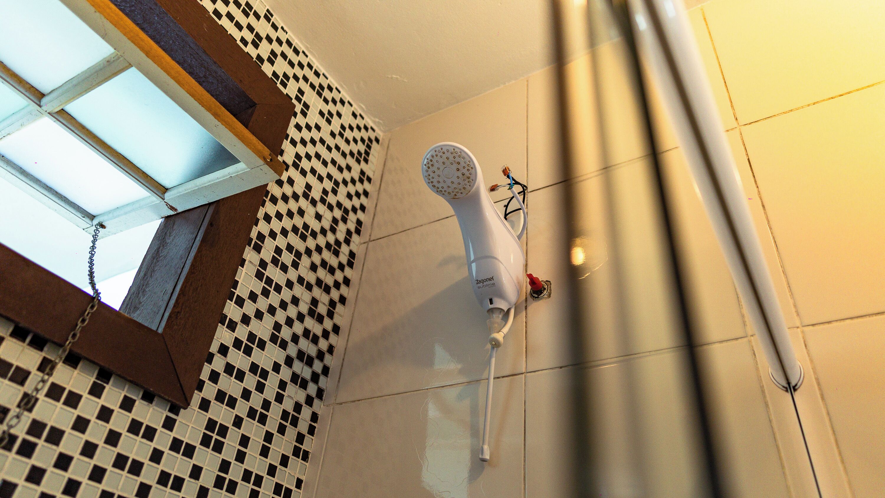 Une salle de bain avec un carrelage à motifs géométriques, une douche blanche et une chaîne visible sur le sol.