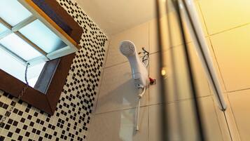 Une salle de bain avec un carrelage à motifs géométriques, une douche blanche et une chaîne visible sur le sol.