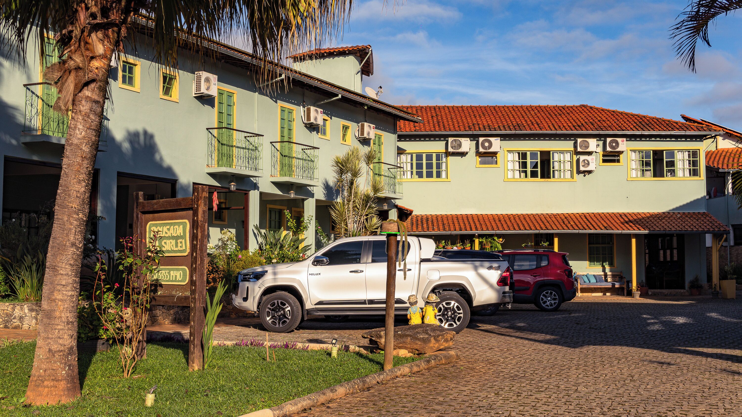 Um edifício com telhado de telhas vermelhas, várias unidades de ar condicionado e uma placa.