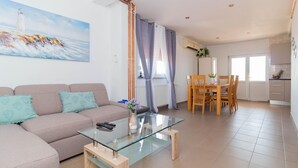 A living room with a sofa, a glass coffee table, and a painting of a lighthouse. - Beautiful apartment in Jasenice with WiFi (Jasenice)