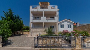 A modern two-story building with a stone facade, a balcony on the upper floor, and a small house-like structure attached to the right. - Beautiful apartment in Jasenice with WiFi (Jasenice)