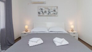 A neatly made bed with two folded towels, white pillows, and two bedside lamps on nightstands. - Beautiful apartment in Jasenice with WiFi (Jasenice)