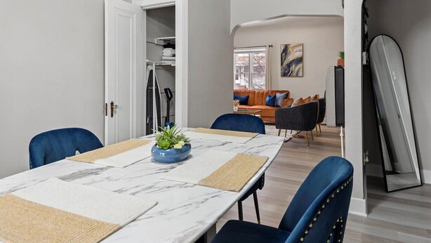 Un comedor moderno con una mesa larga, sillas azules y un centro de mesa con planta decorativa.