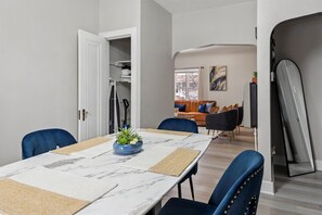 Un comedor moderno con una mesa larga, sillas azules y un centro de mesa con planta decorativa.